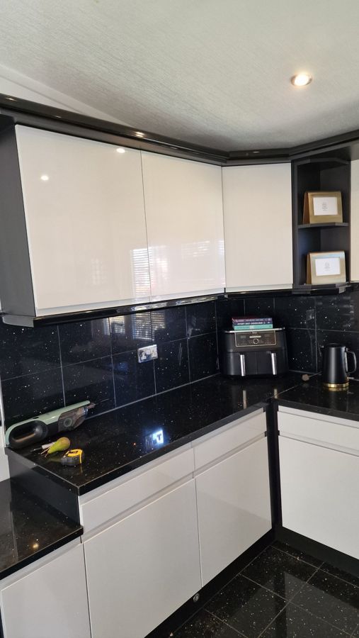 Light grey gloss wall units with black sparkle splashback